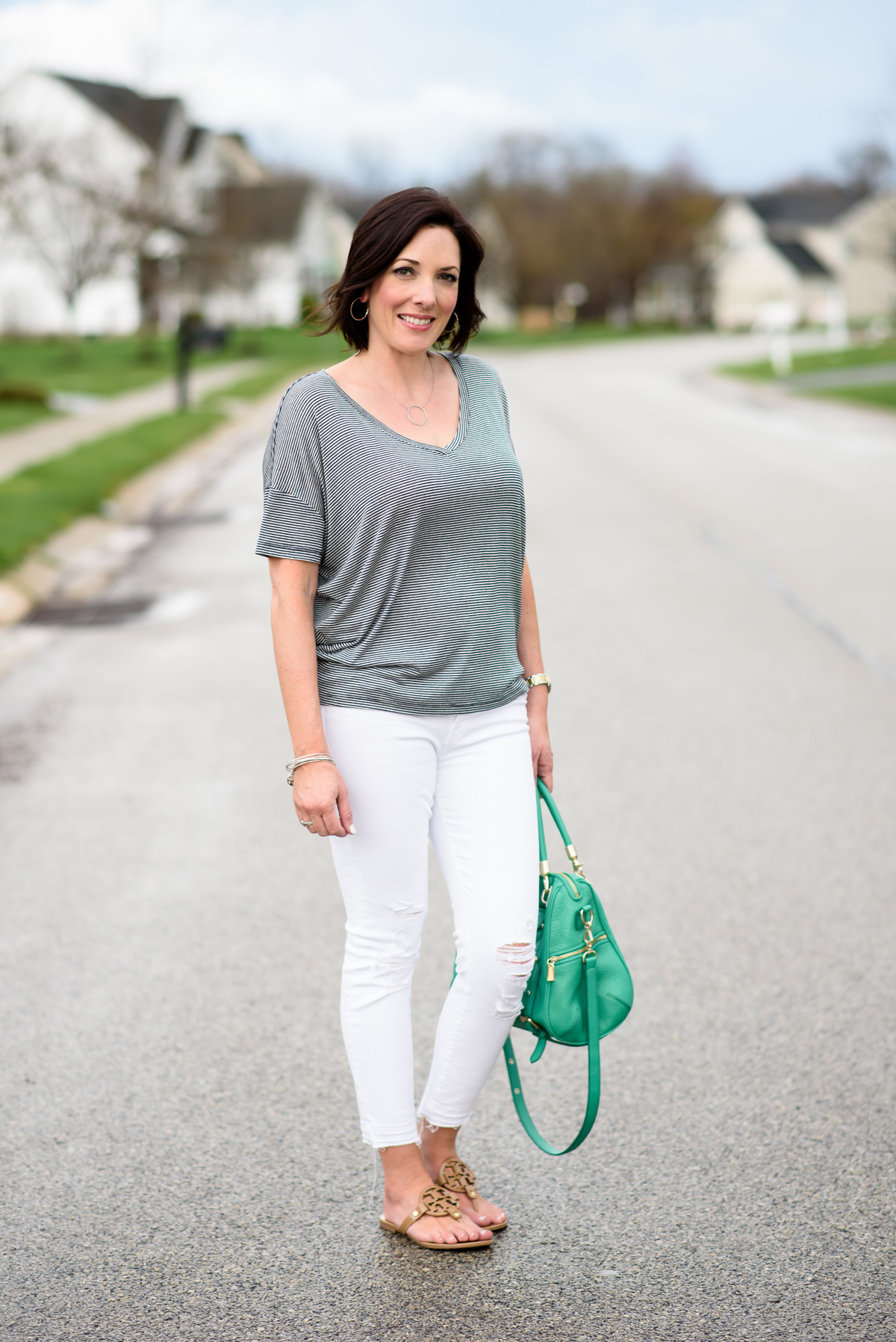 Casual Spring Outfits for Women Over 40: Navy and White Stripe Dolman Sleeve Top with White Jeans and a green handbag