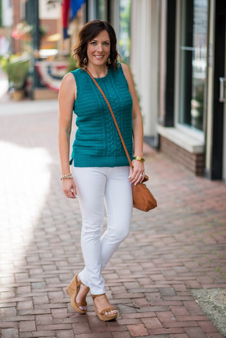 This gorgeous teal sleeveless sweater outfit with white jeans and cognac accessories is perfect for summer, and the sweater is also a great transition piece for fall.