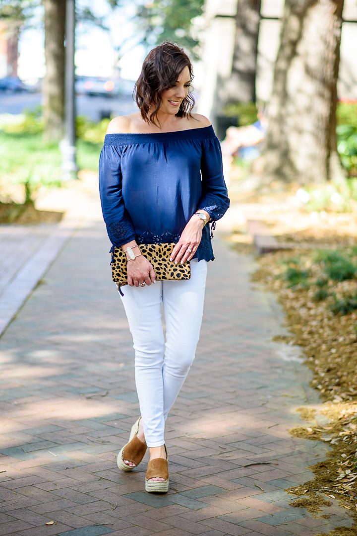 I'm styling a navy eyelet off-the-shoulder top with white jeans and chestnut espadrille wedges. The leopard clutch and chandelier earrings make it perfect for date night!