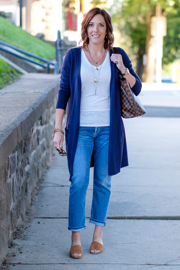 Jo-Lynne Shane styling slim boyfriend jeans for fall with a long navy cardigan and cognac suede slides. 